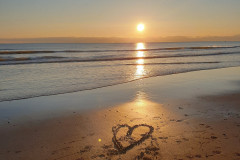 sandstrand-sonnenuntergang-herzform-wasser